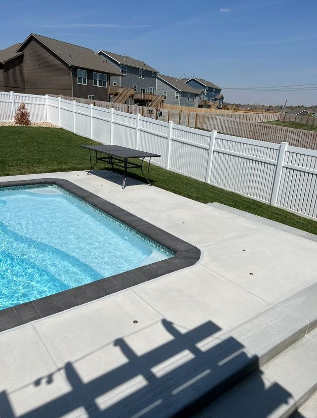 A large swimming pool with a white fence around it
