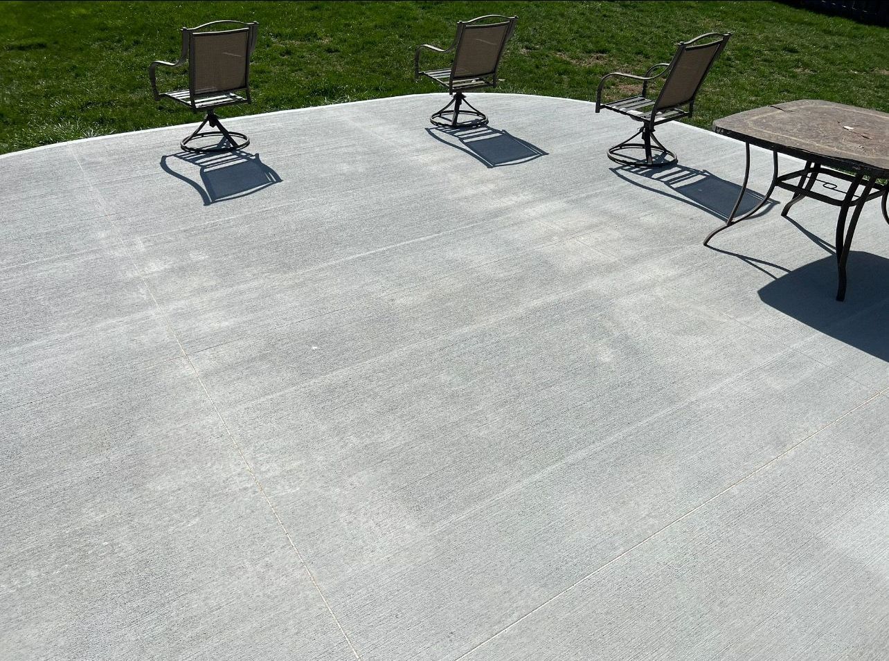 There are three chairs and a table on the patio