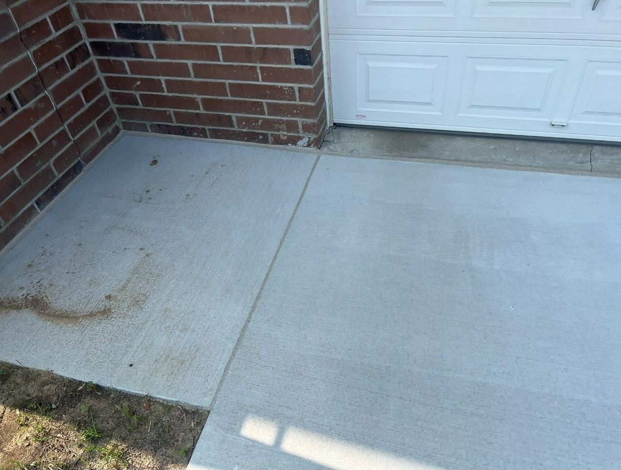 A white garage door is next to a brick wall