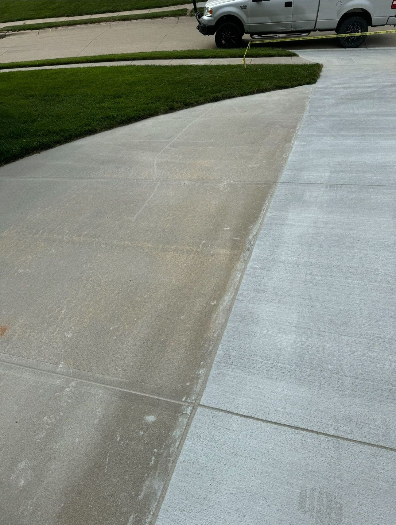 A white truck is parked on the side of a concrete driveway