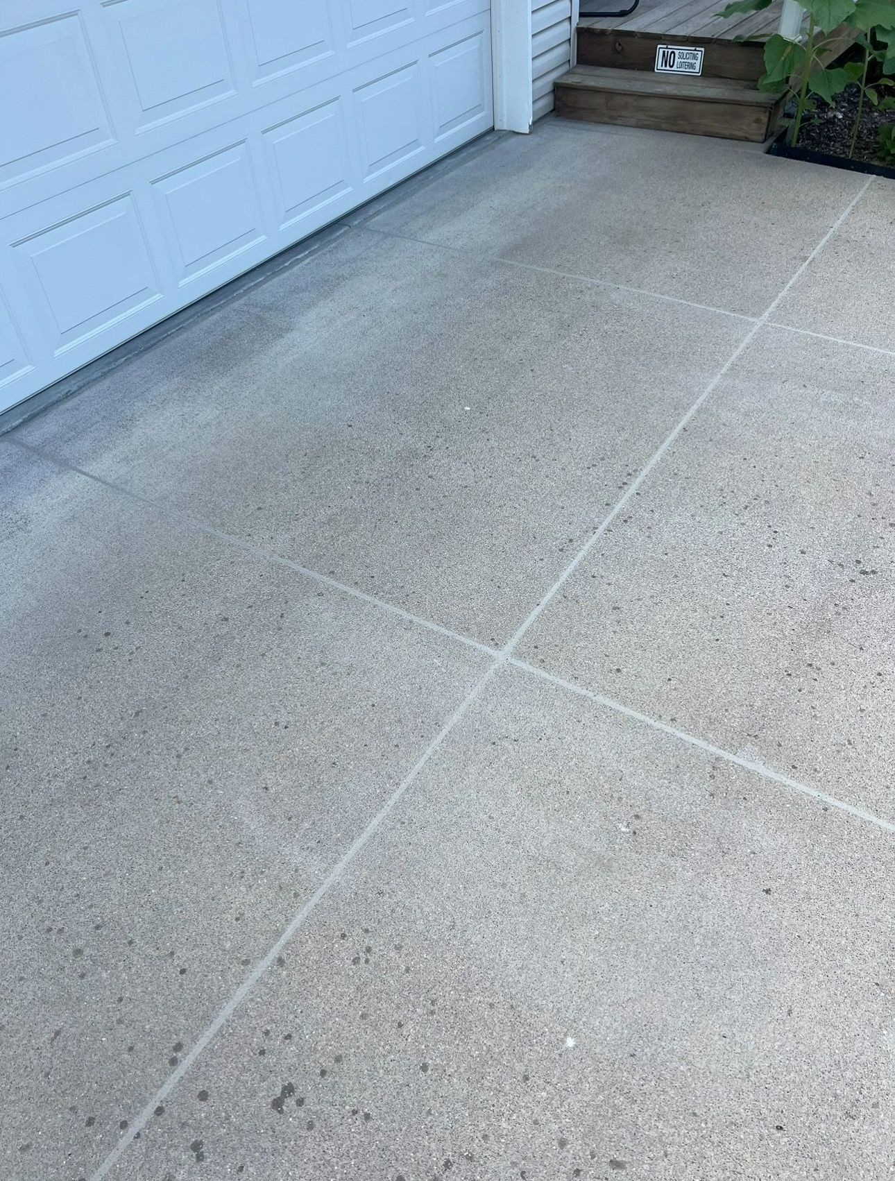 A concrete driveway next to a garage door and steps