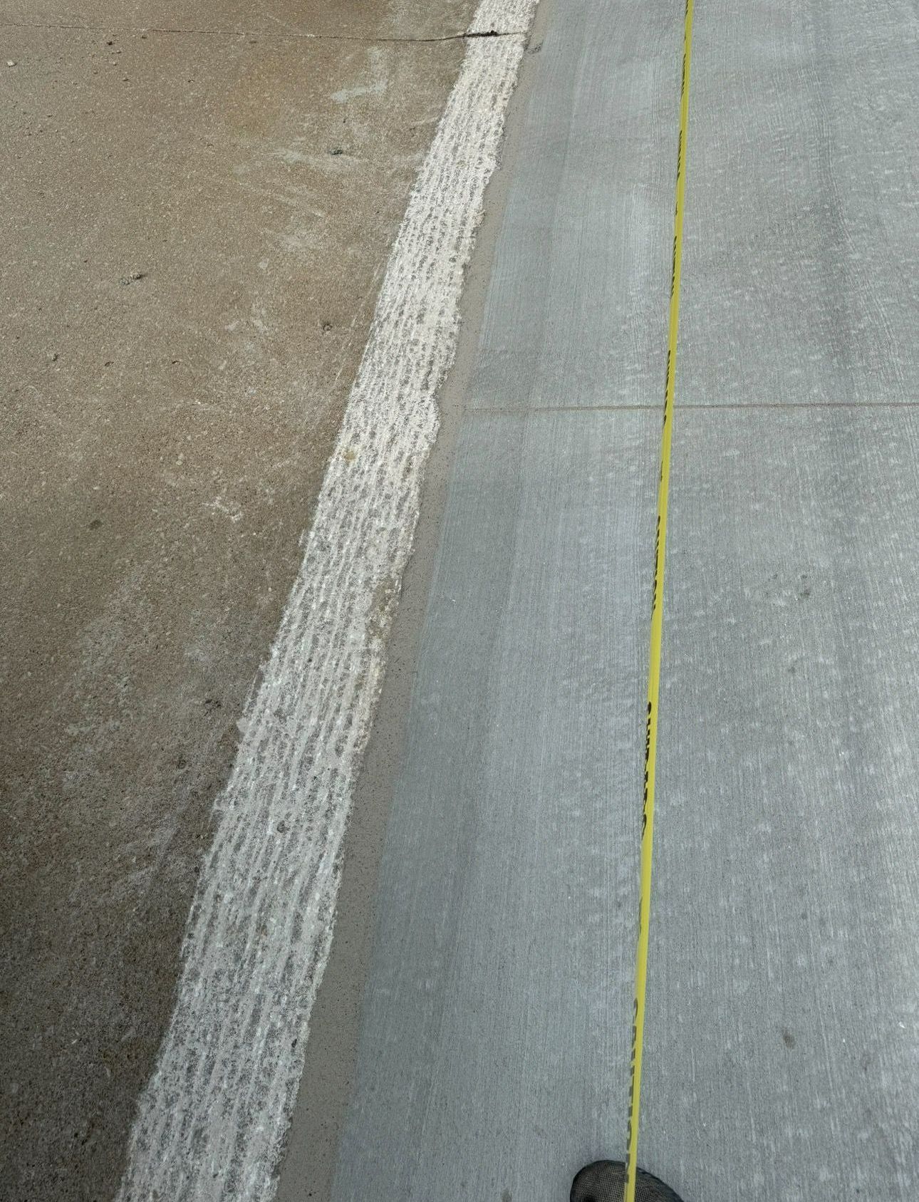 A yellow tape measure is laying on a concrete surface
