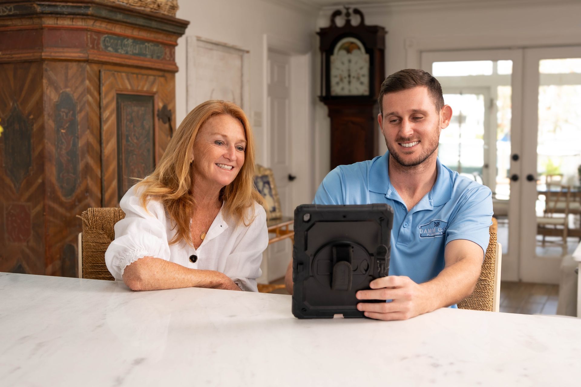 Plumber inspecting sink pipes with pliers, looking intently. Bathroom setting, plumbing fixtures visible.