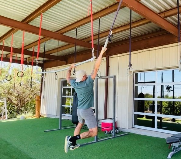 A woman is pushing a sled with a tire in the background.