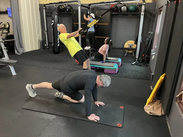 A group of people is doing circuit fusion exercises in a gym.