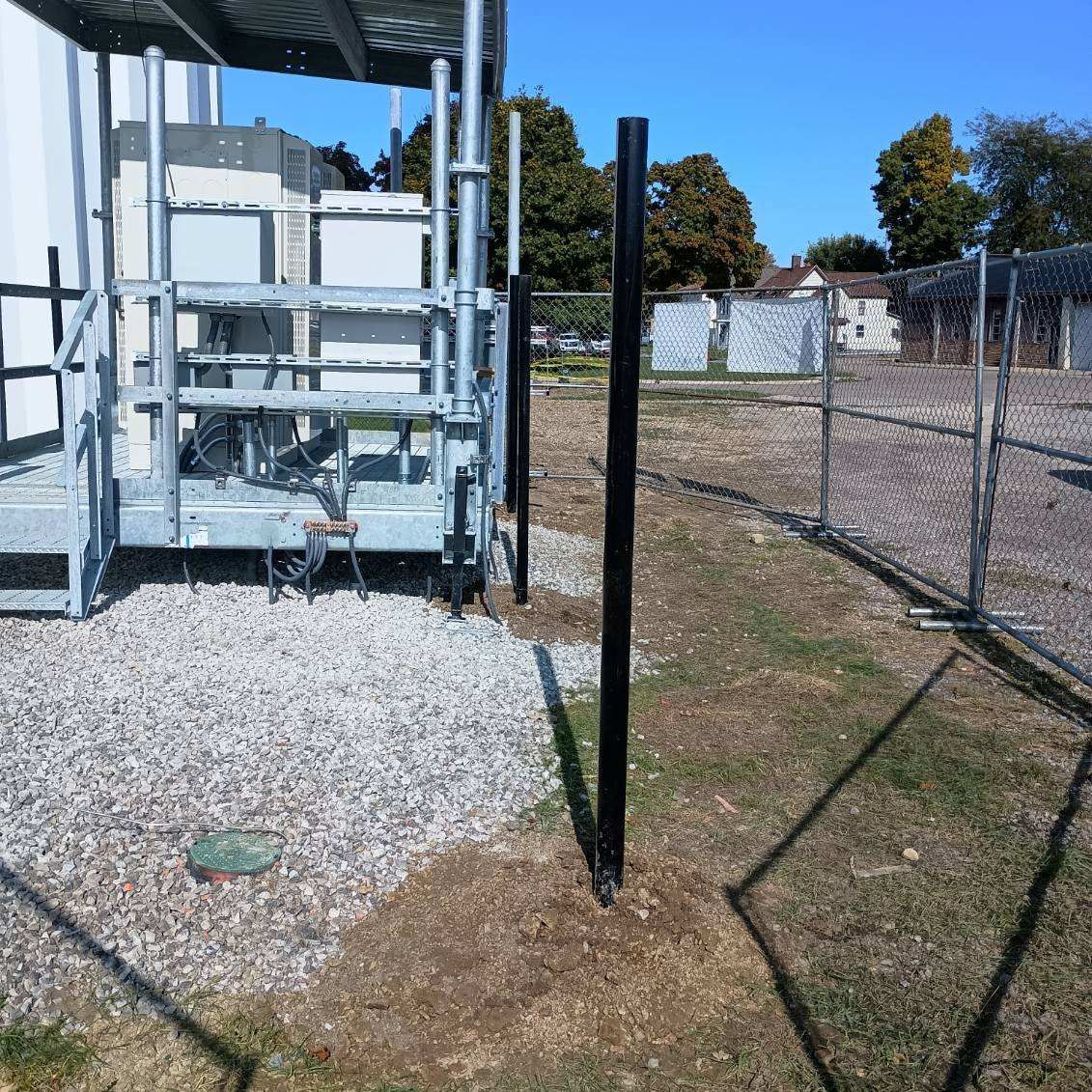A fence surrounds a gravel area with a building in the background