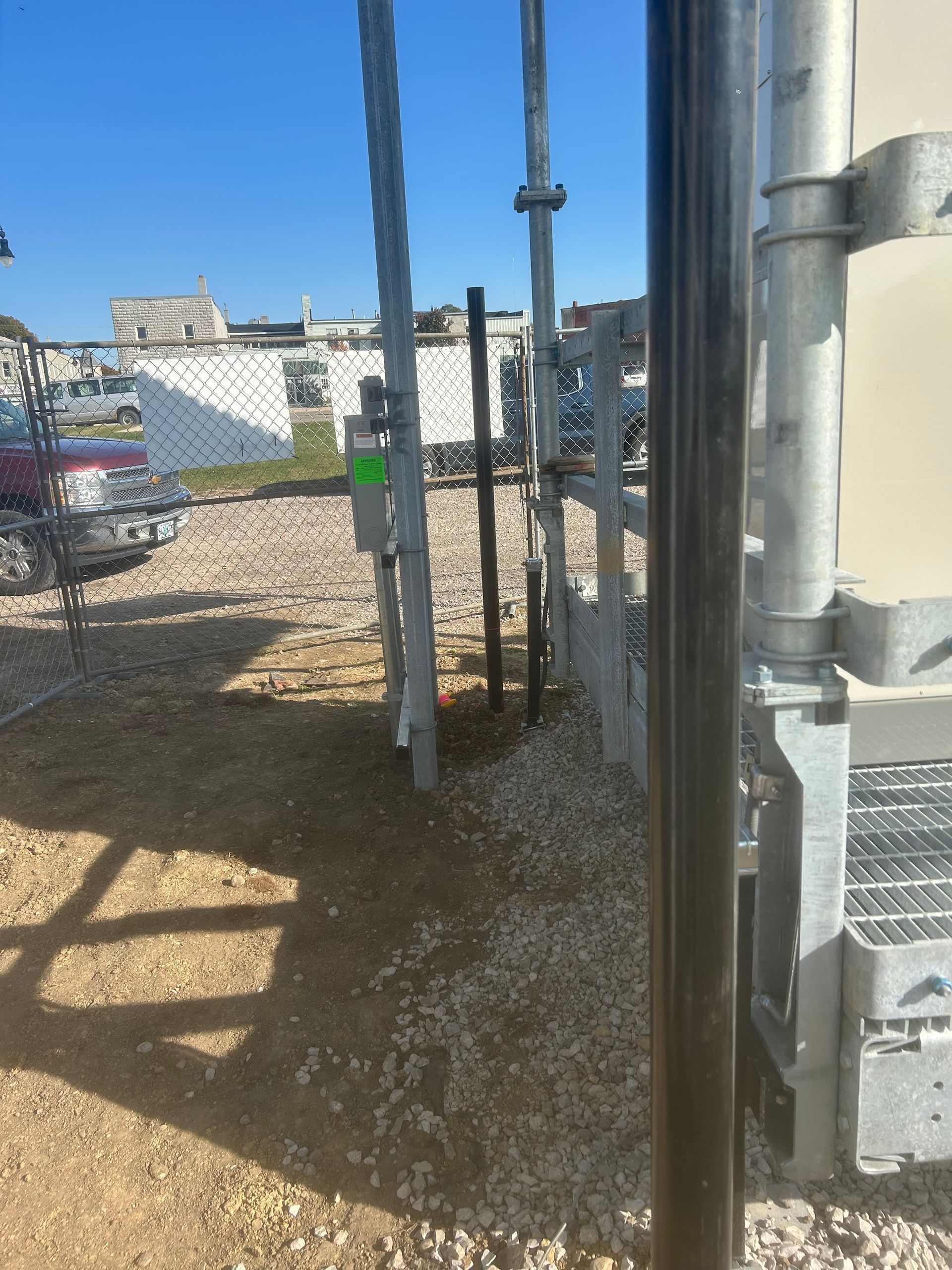 A truck is parked in a gravel lot next to a fence