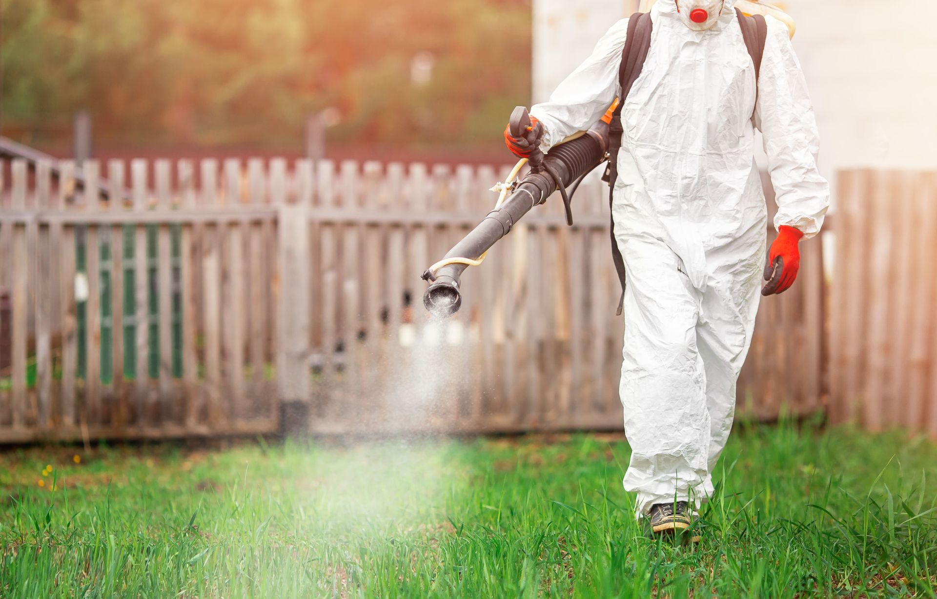 Pest control technician applying pesticide to a customer's lawn.