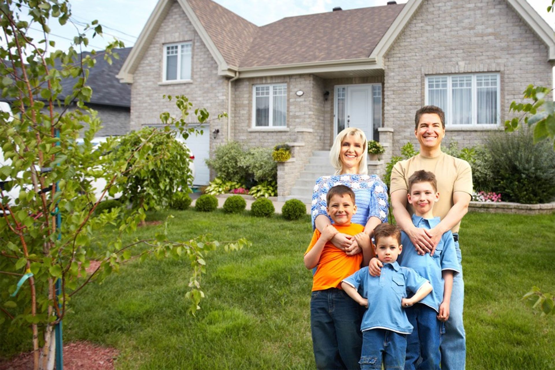 A family is posing for a picture in front of their house