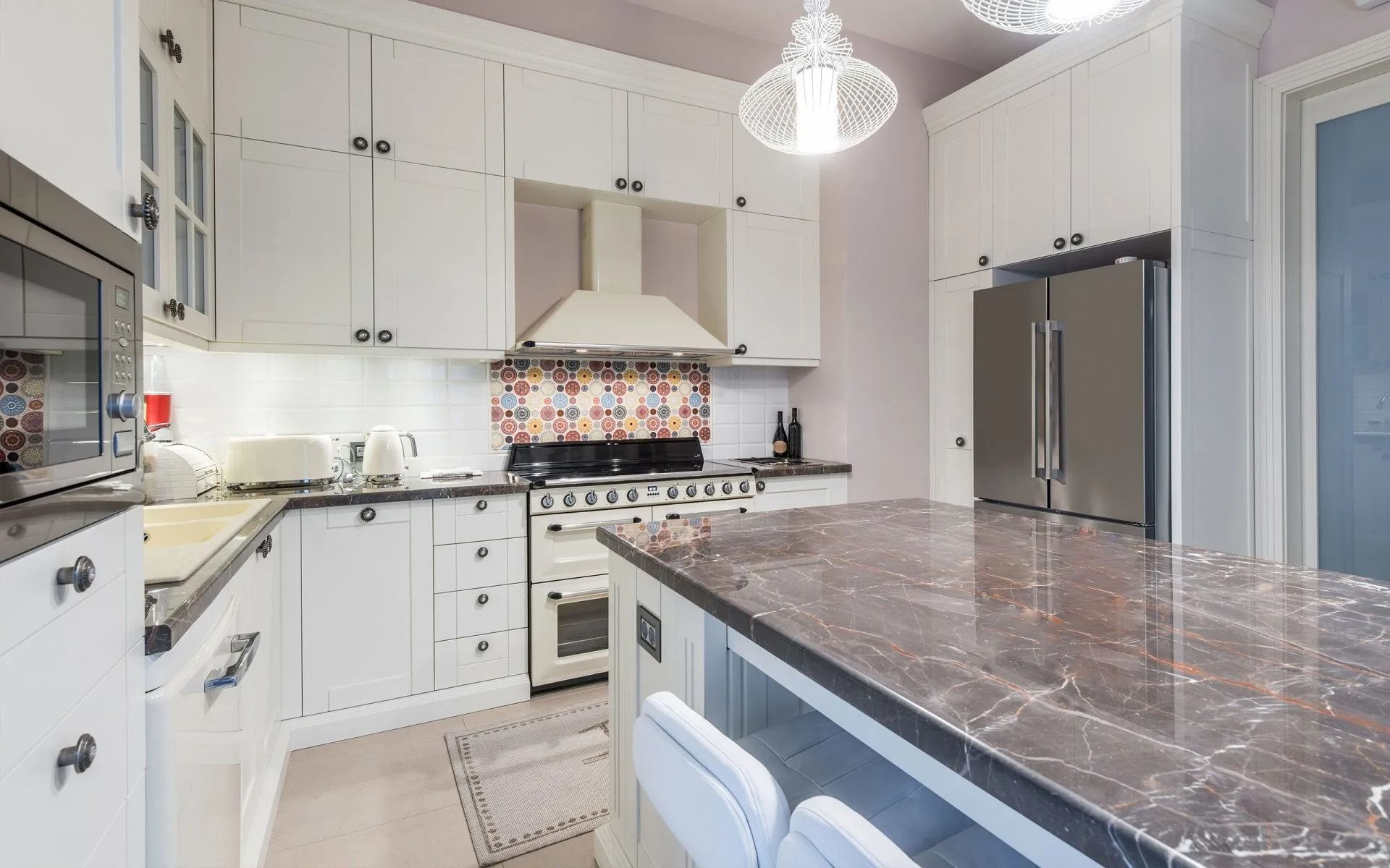 A kitchen with white cabinets and a marble counter top.