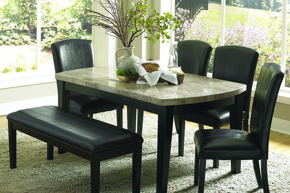 A marble dining table with black chairs and a bench