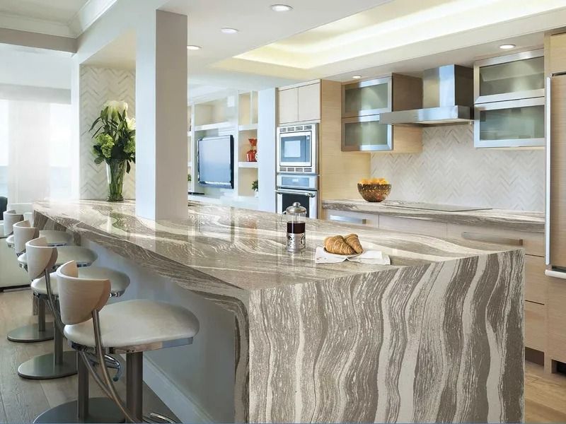 A kitchen with a marble counter top and stools