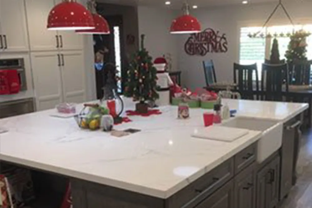 A kitchen with a large island and a sink and a christmas tree on the counter.