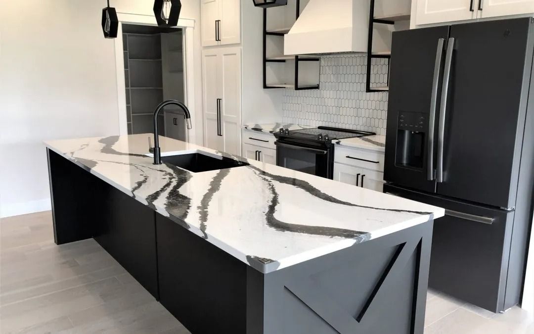 A kitchen with a large island , sink , refrigerator and stove.