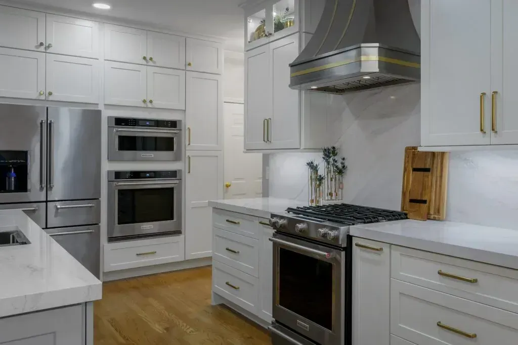 Modern white kitchen with stainless steel appliances, countertops, and wood floor.
