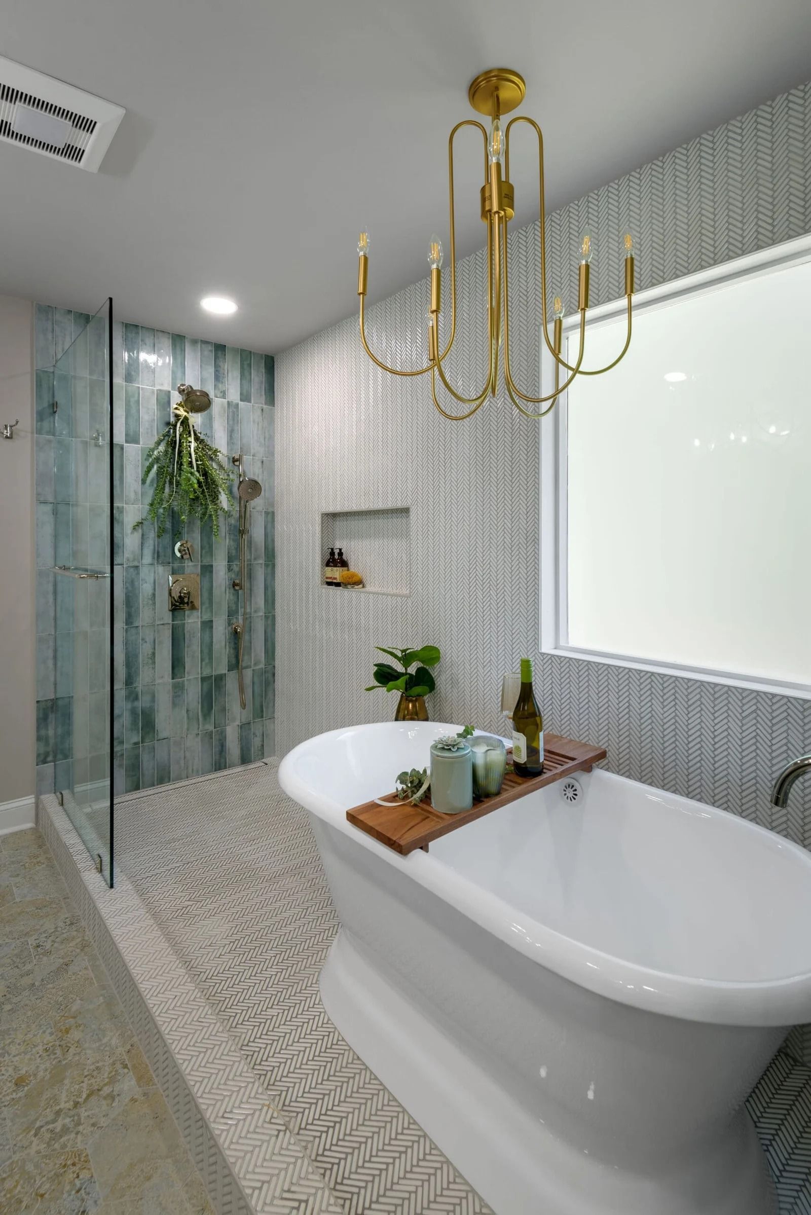 Elegant white bathroom with freestanding tub, gold chandelier, and patterned tile.