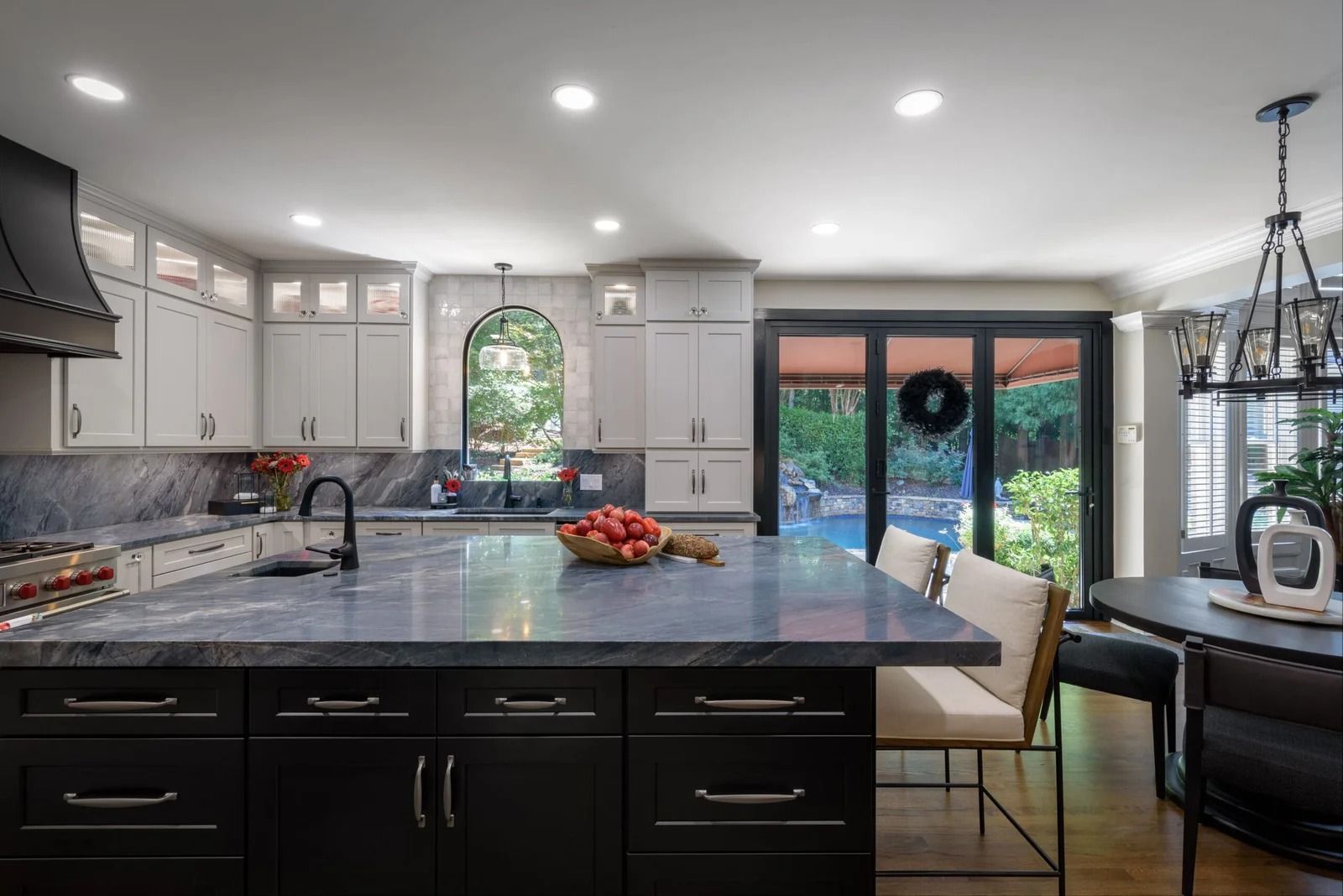 Modern kitchen with dark cabinetry, gray countertops, and a view of a pool area.