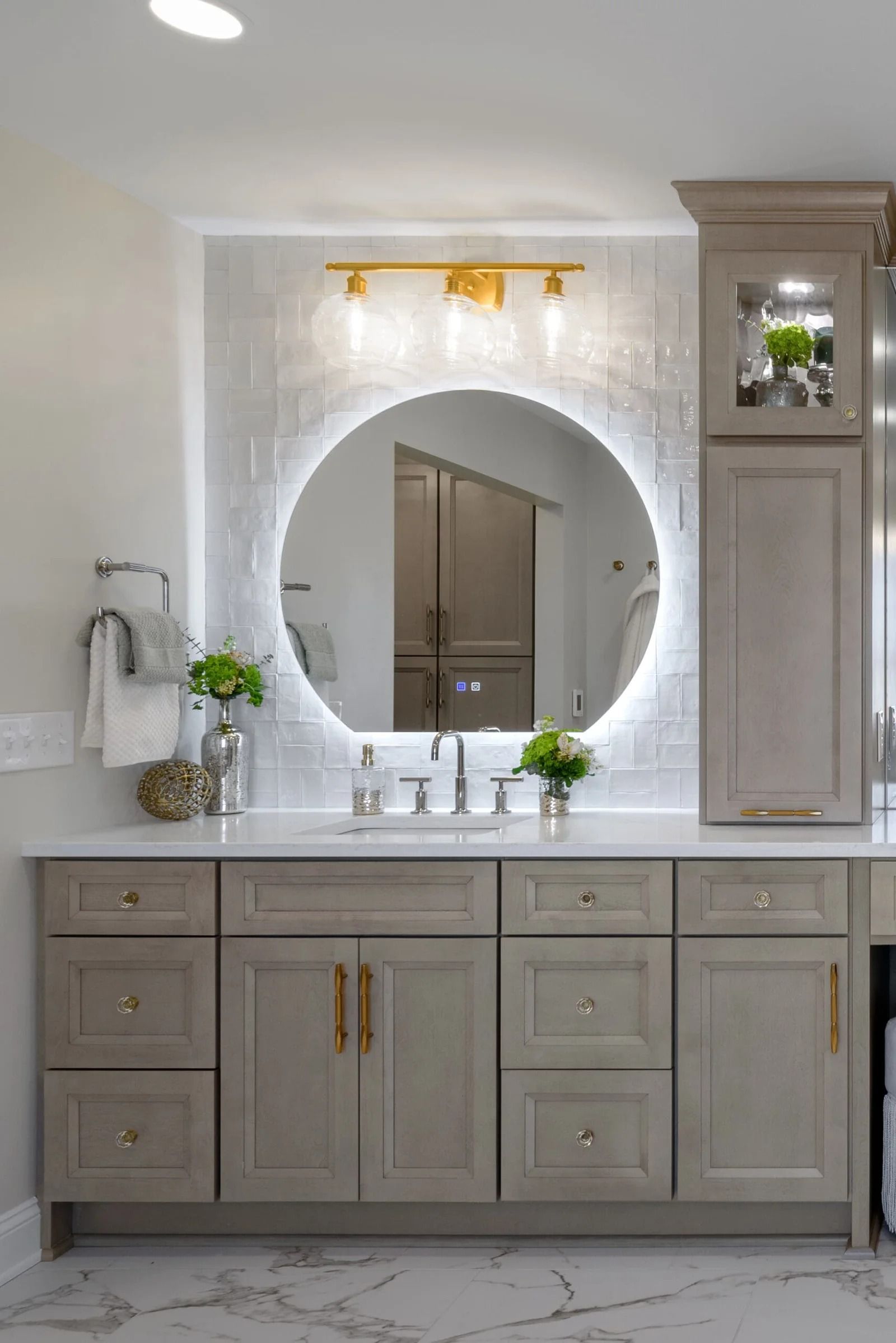 Bathroom vanity with a round, backlit mirror and gold accents.