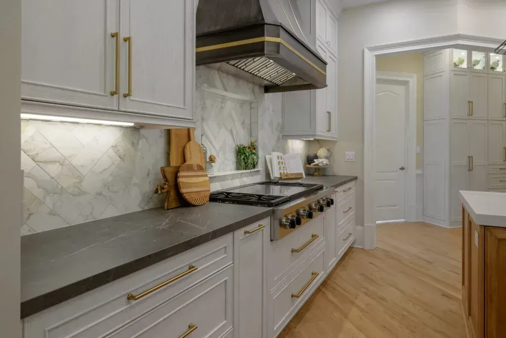 Kitchen with gray countertops, white cabinets, and gold hardware.