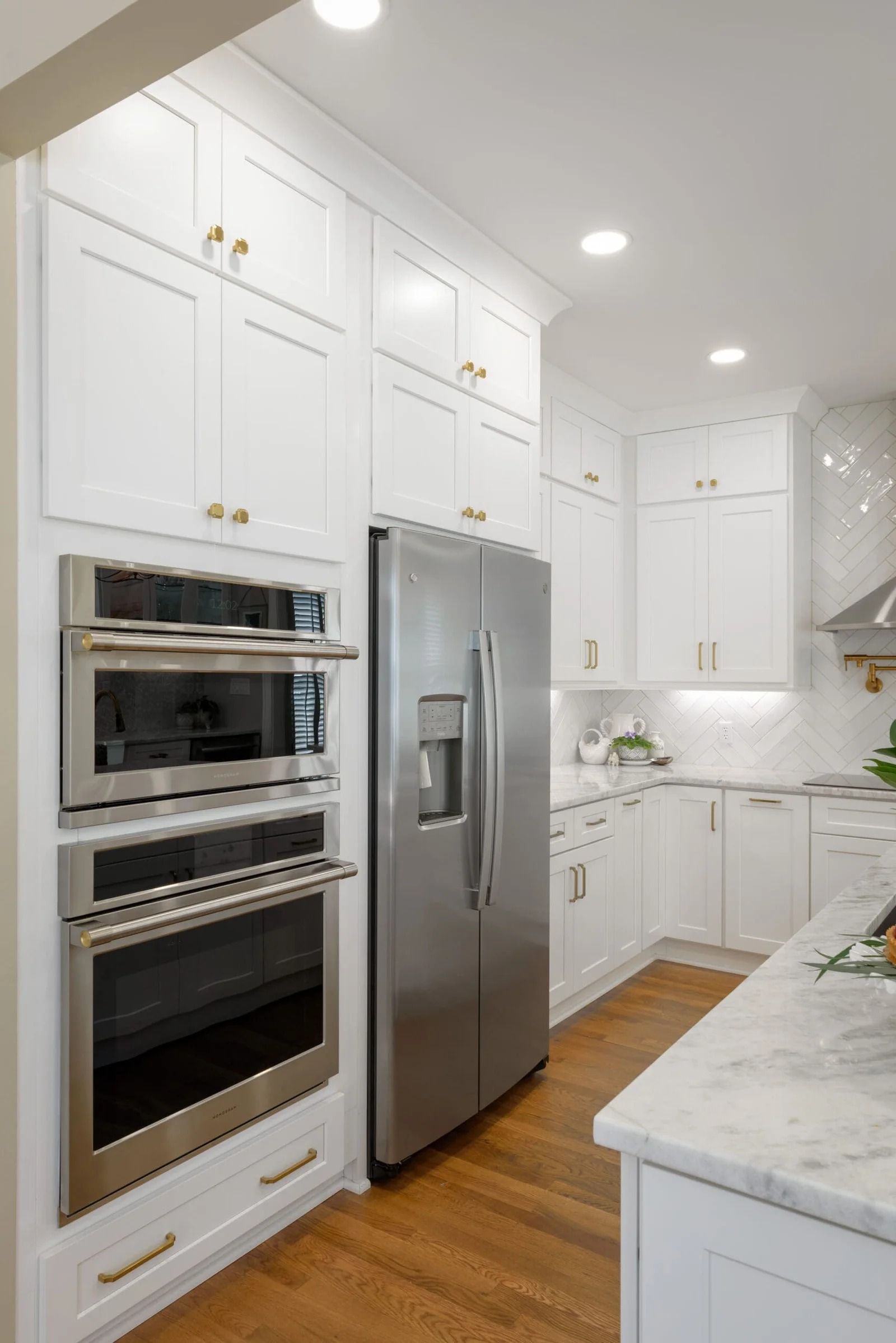 White kitchen with stainless steel appliances and wood floors.