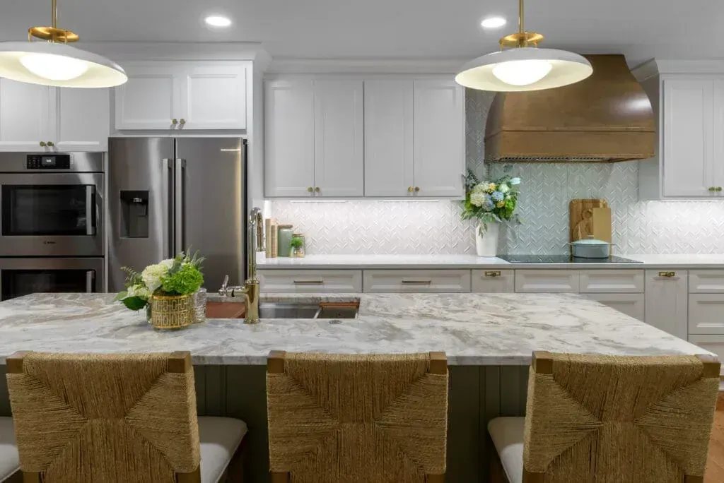 Kitchen with white cabinets, large island, granite countertops, and woven bar stools.