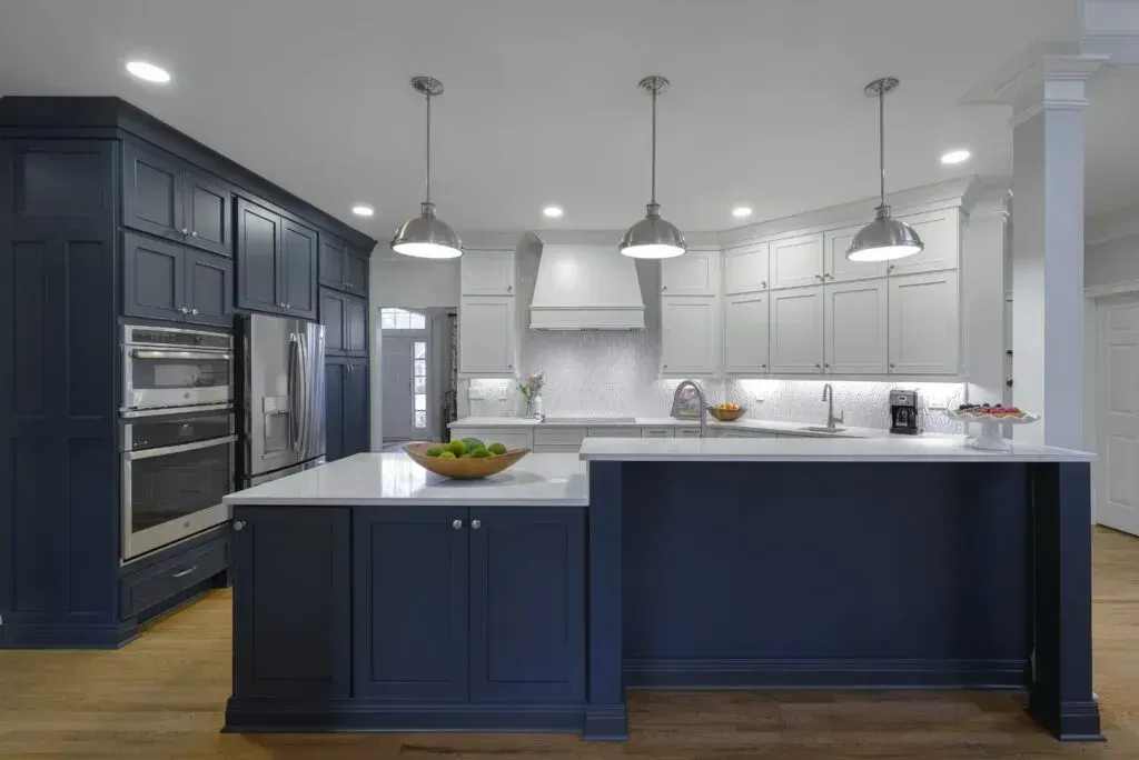 Modern kitchen with blue and white cabinets, stainless steel appliances, and a central island.