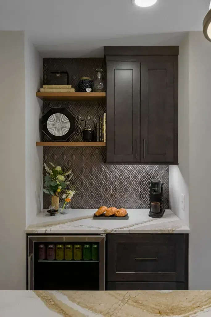 Built-in coffee station with dark cabinetry, shelving, and a small refrigerator, set into a wall.