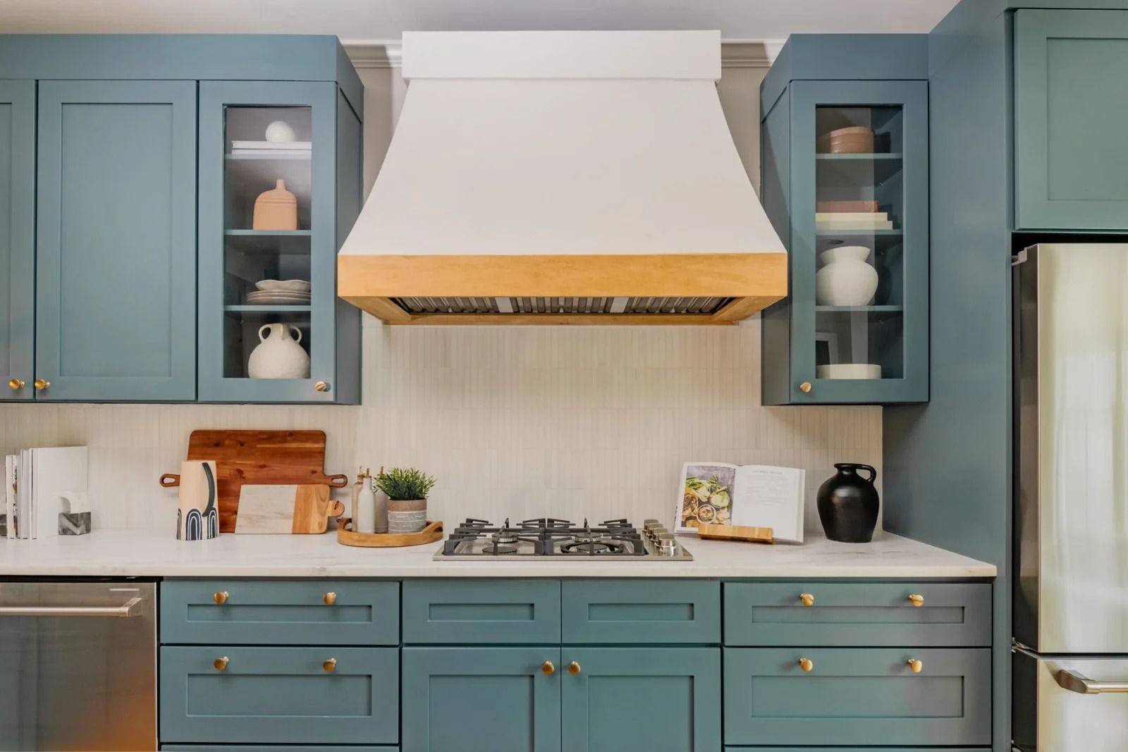 Blue kitchen cabinets, white range hood, and marble countertop.