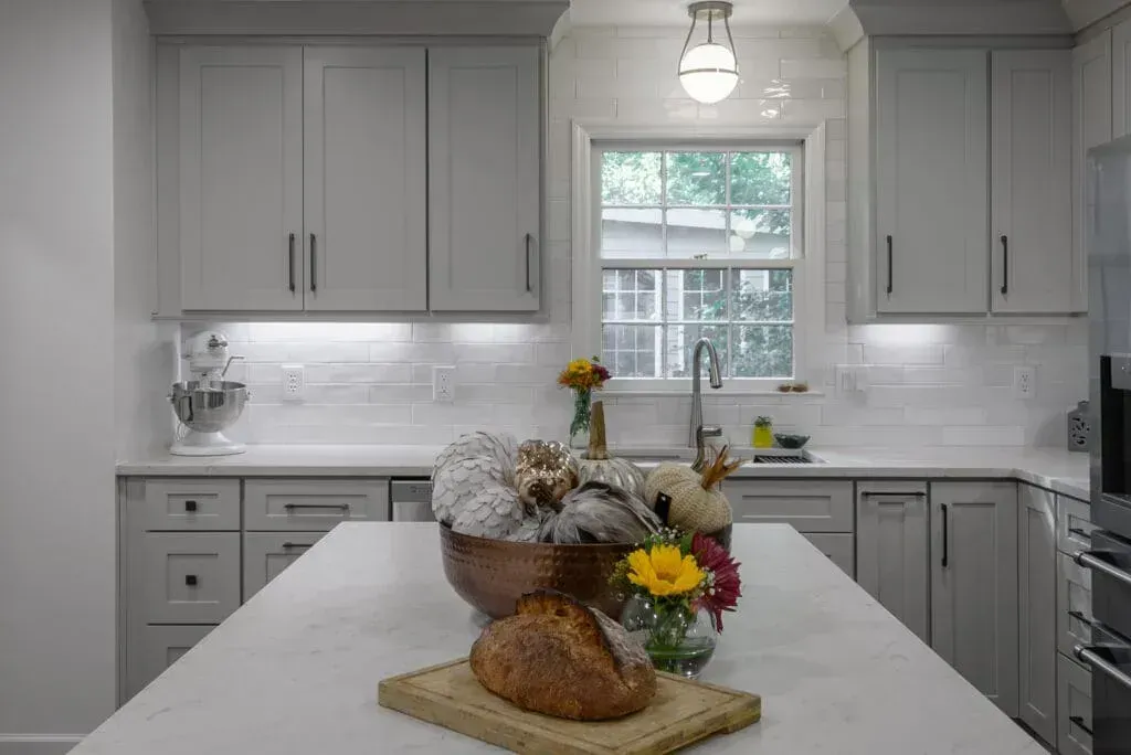 Gray kitchen with island, cabinets, window, and bread.