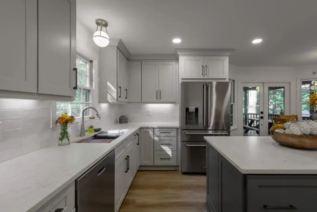 Modern kitchen with gray cabinets, white countertops, stainless steel appliances, and an island.