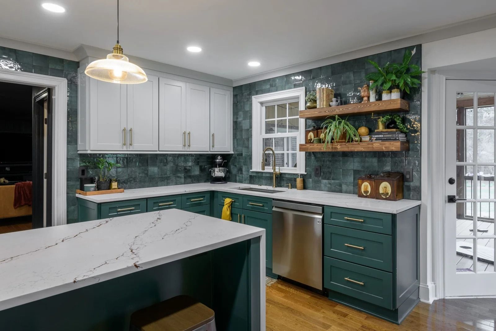 Green and white kitchen remodel with dark green cabinets, white countertops, and a stainless steel dishwasher.