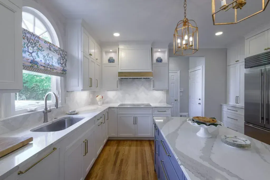 Bright, modern kitchen with white cabinets, marble countertops, and a blue island.