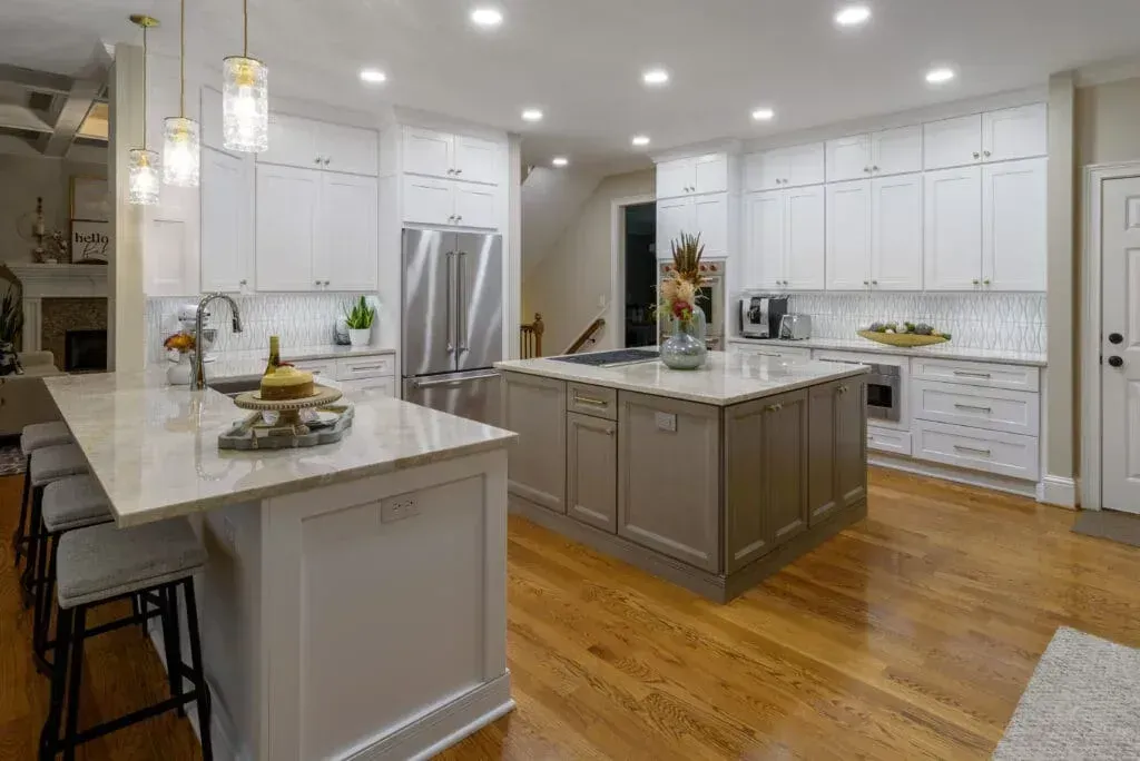 Modern kitchen with white cabinets, gray island, and wood floors.