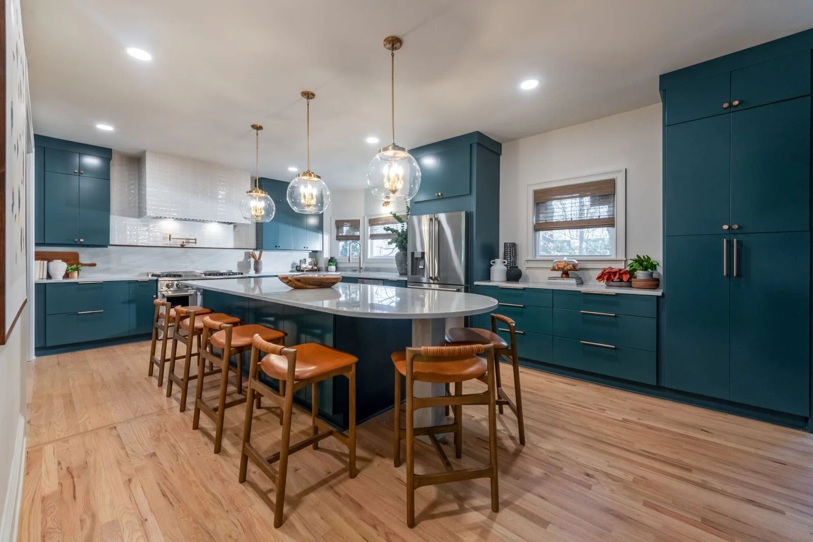 Modern kitchen with teal cabinets, large island with seating, and pendant lights.