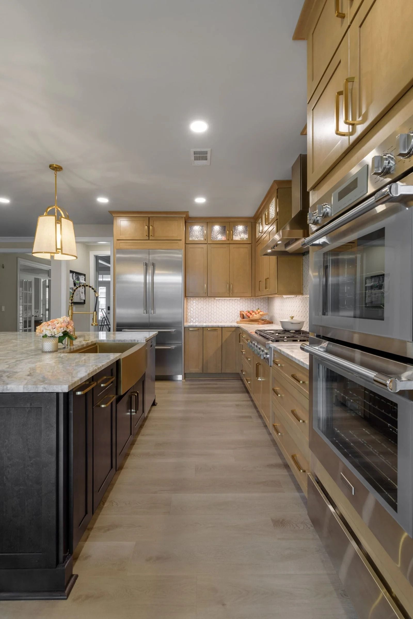 Modern kitchen with light wood cabinets, stainless steel appliances, and a dark island.