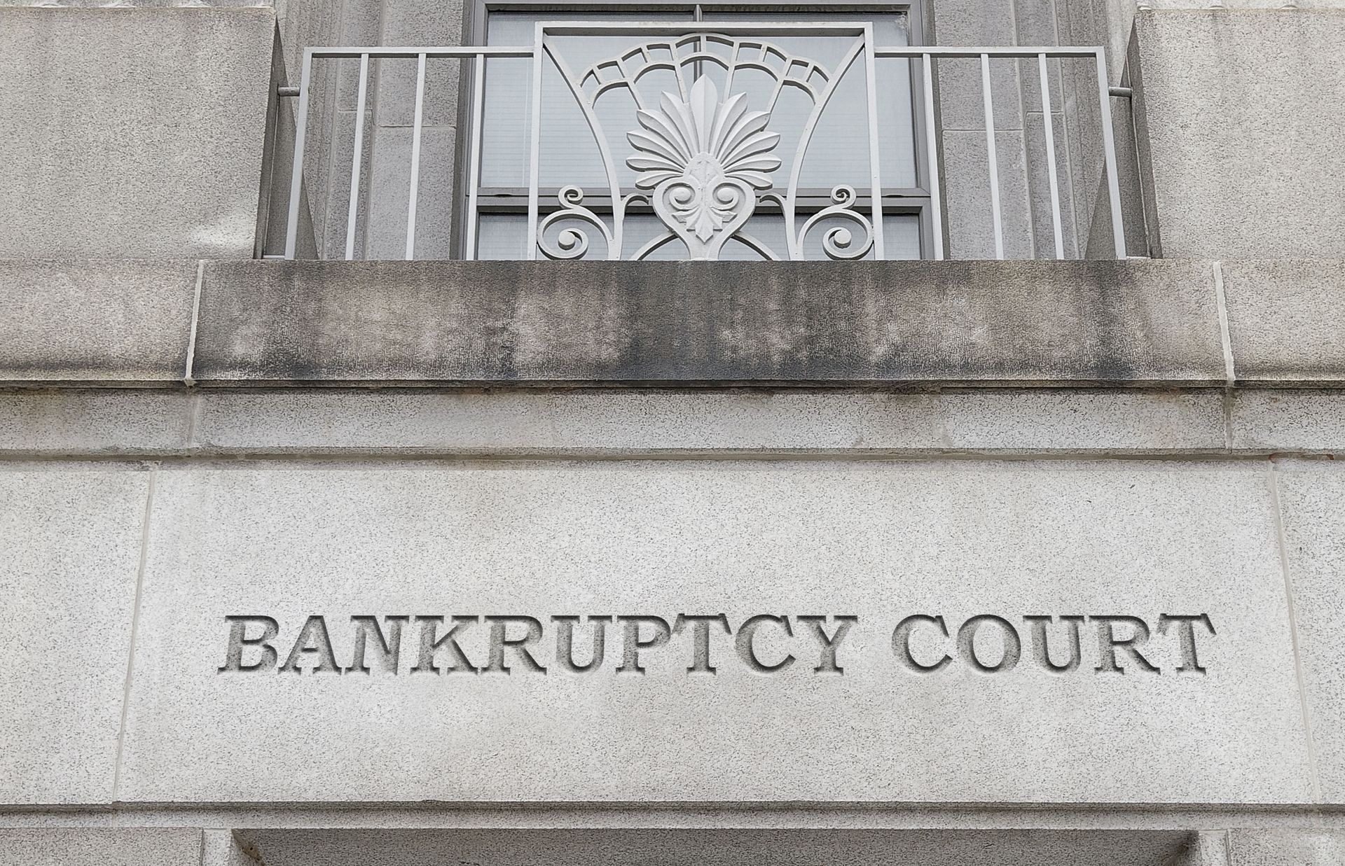 Stone building facade with a “BANKRUPTCY COURT” sign beneath a balcony railing