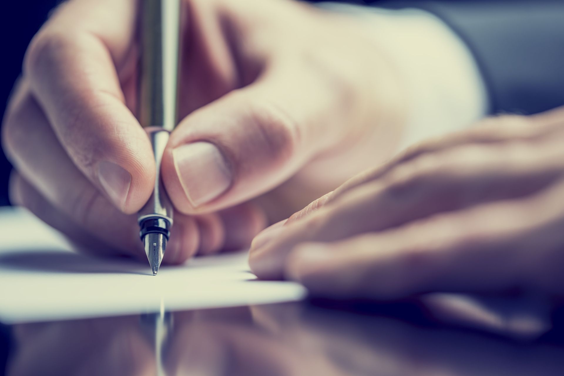 Hands signing a document with a pen on a desk