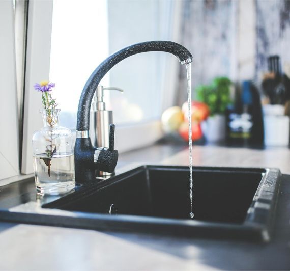 A kitchen sink with water running from the faucet