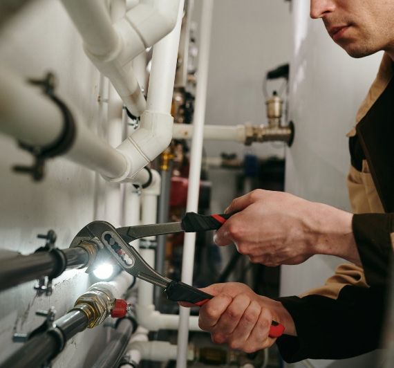 A man is working on a pipe with a wrench.