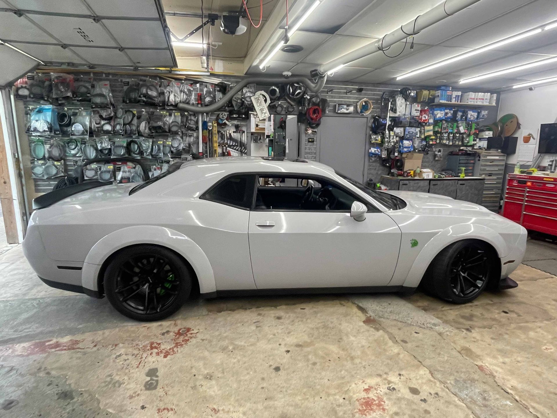 A white dodge challenger is parked in a garage.