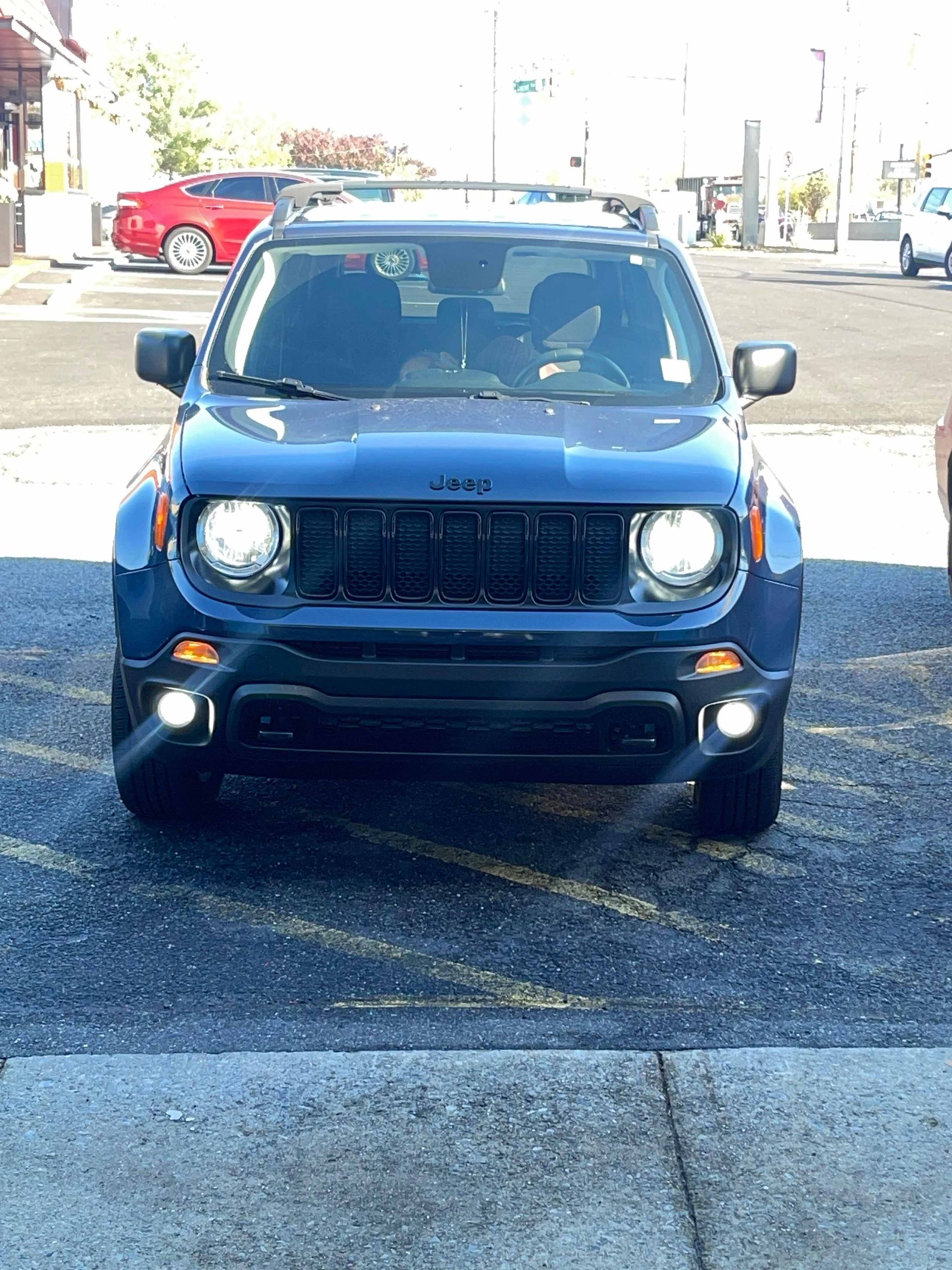 A blue jeep renegade is parked in a parking lot.
