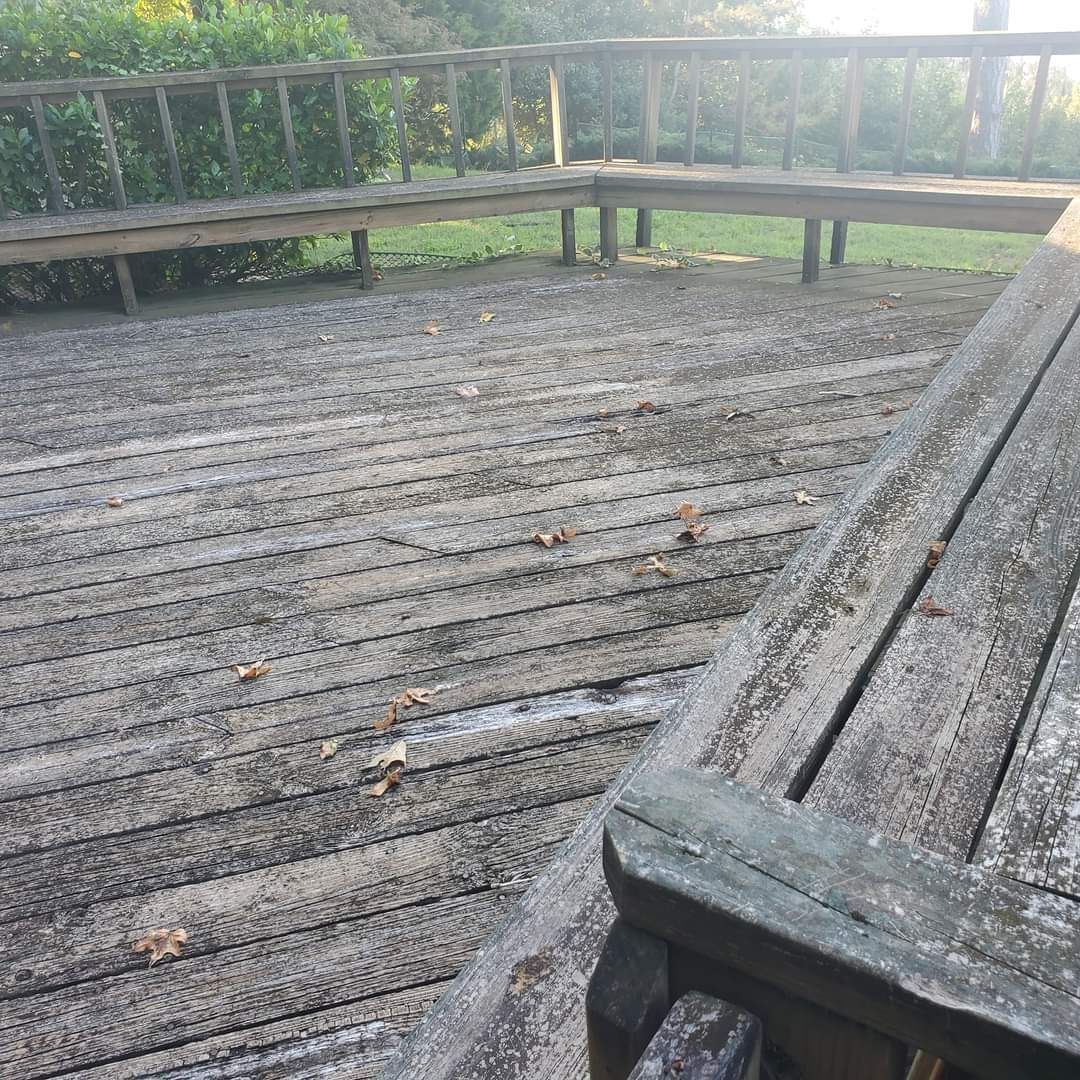 Weathered wooden boardwalk with benches overlooking a sandy, debris-strewn area in soft sunlight