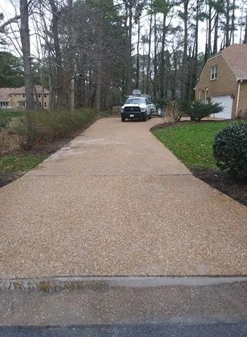 Long driveway leading to a house, with a parked black SUV near the end and trees lining the sides.