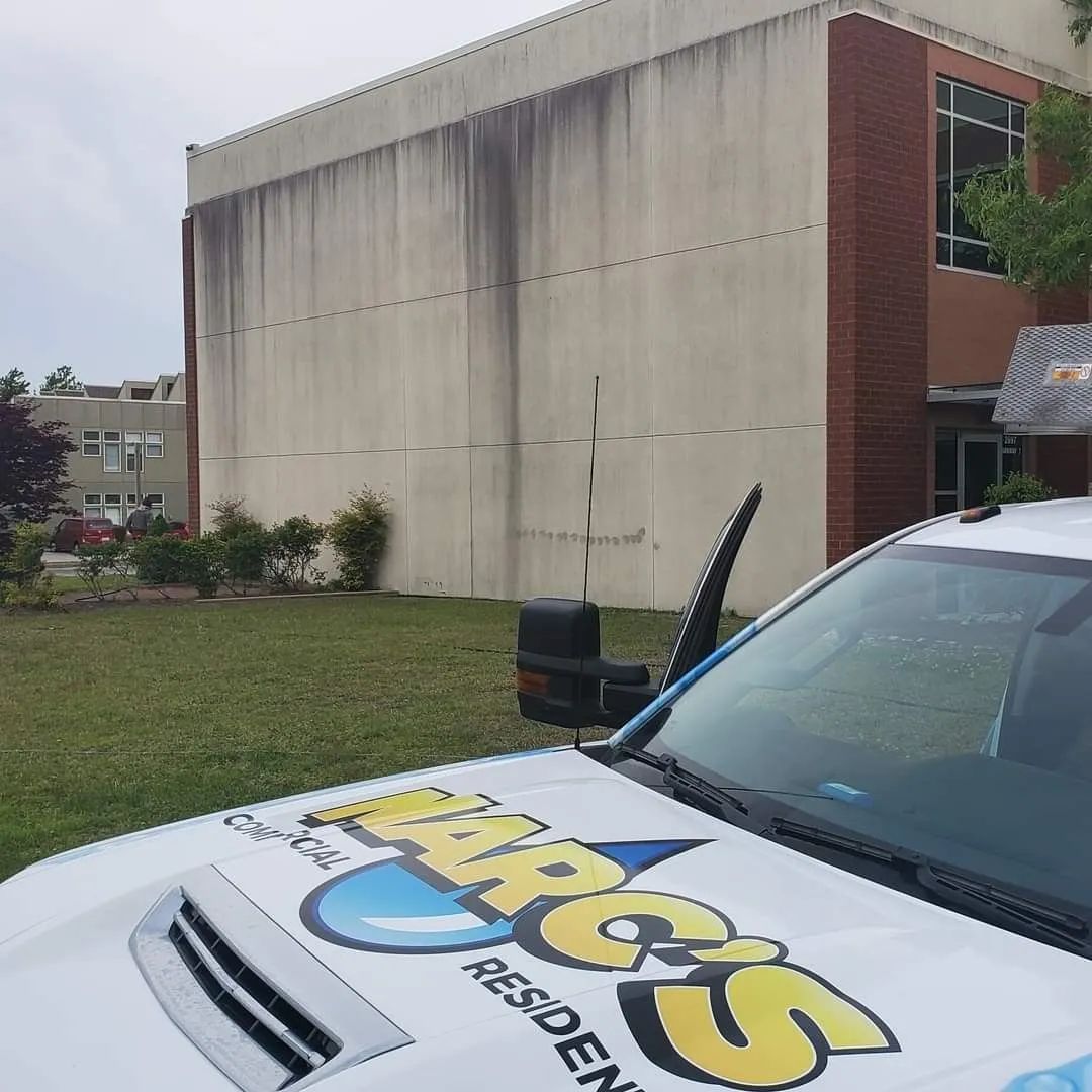 Delivery car with “ARIES” logo parked beside a plain concrete building and grassy lawn