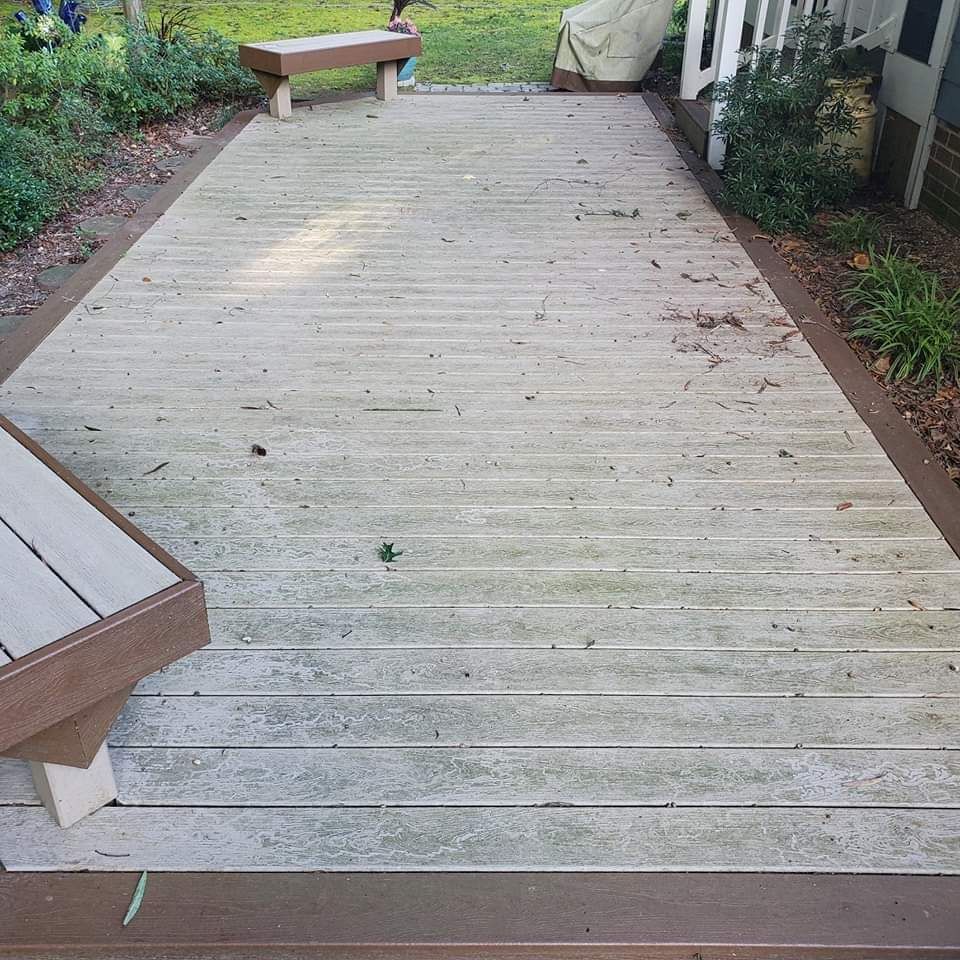 Wooden deck walkway with benches, bordered by shrubs and a white railing