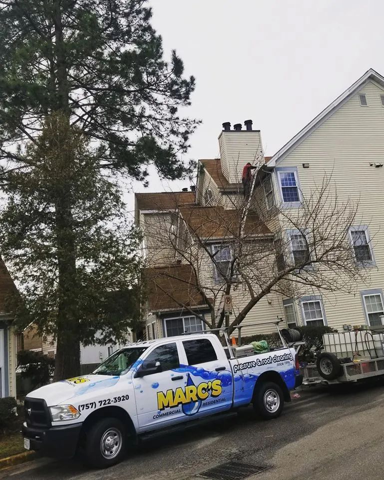 MARC'S service truck parked beside a house with a trailer and ladder under overcast skies