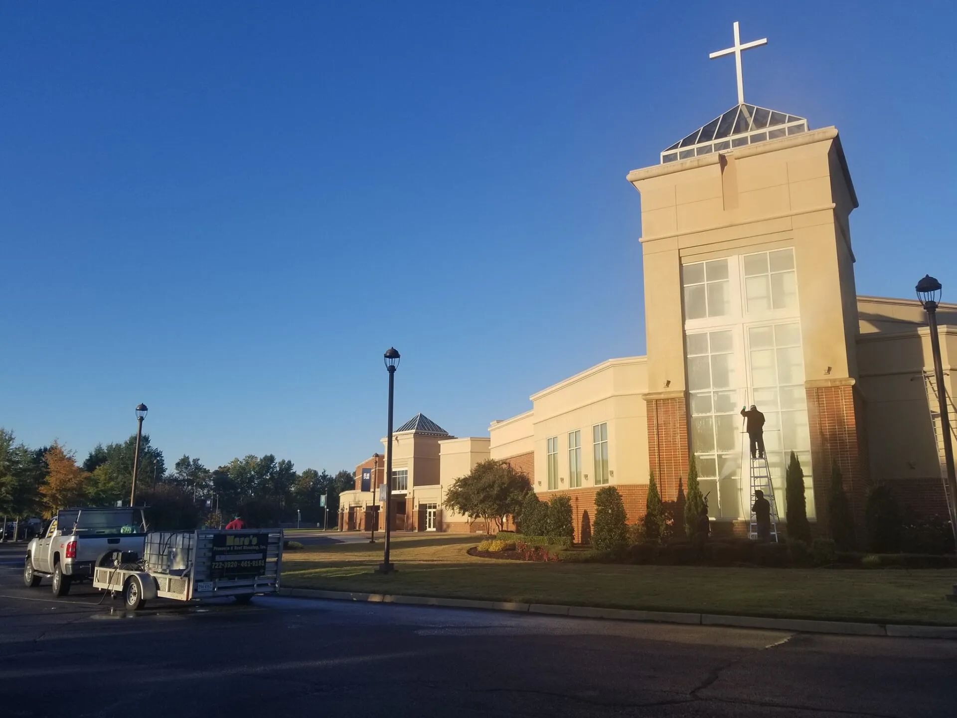 Church building with a large cross on top beside a street at sunset