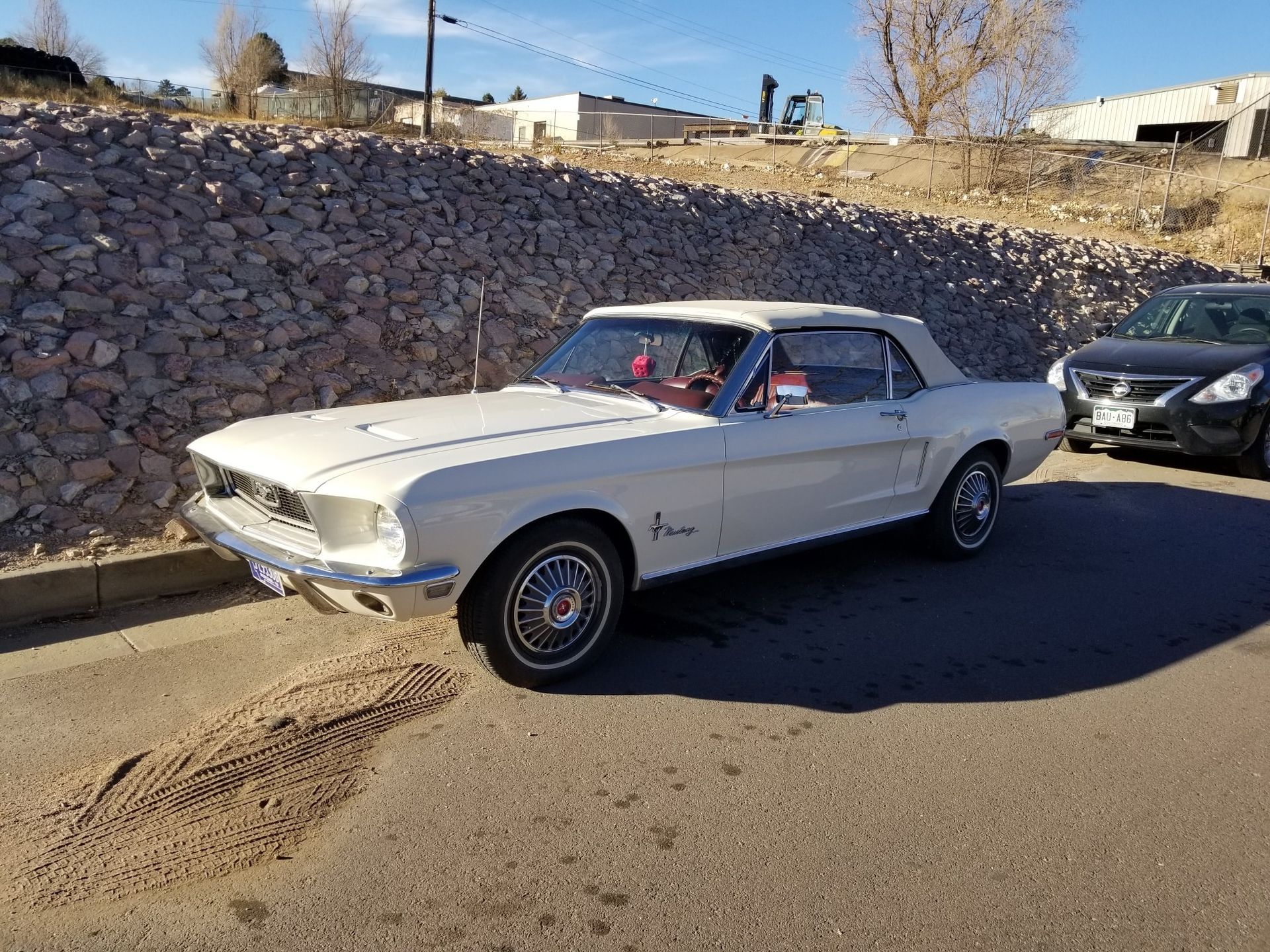 White classic Ford Mustang convertible parked on a sunny day.