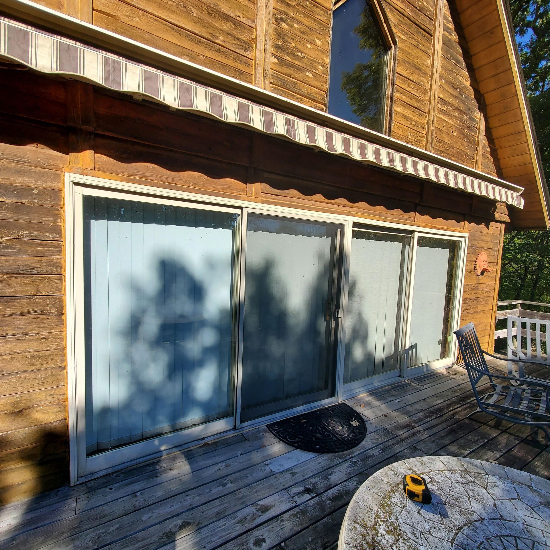A wooden house with sliding glass doors and an awning