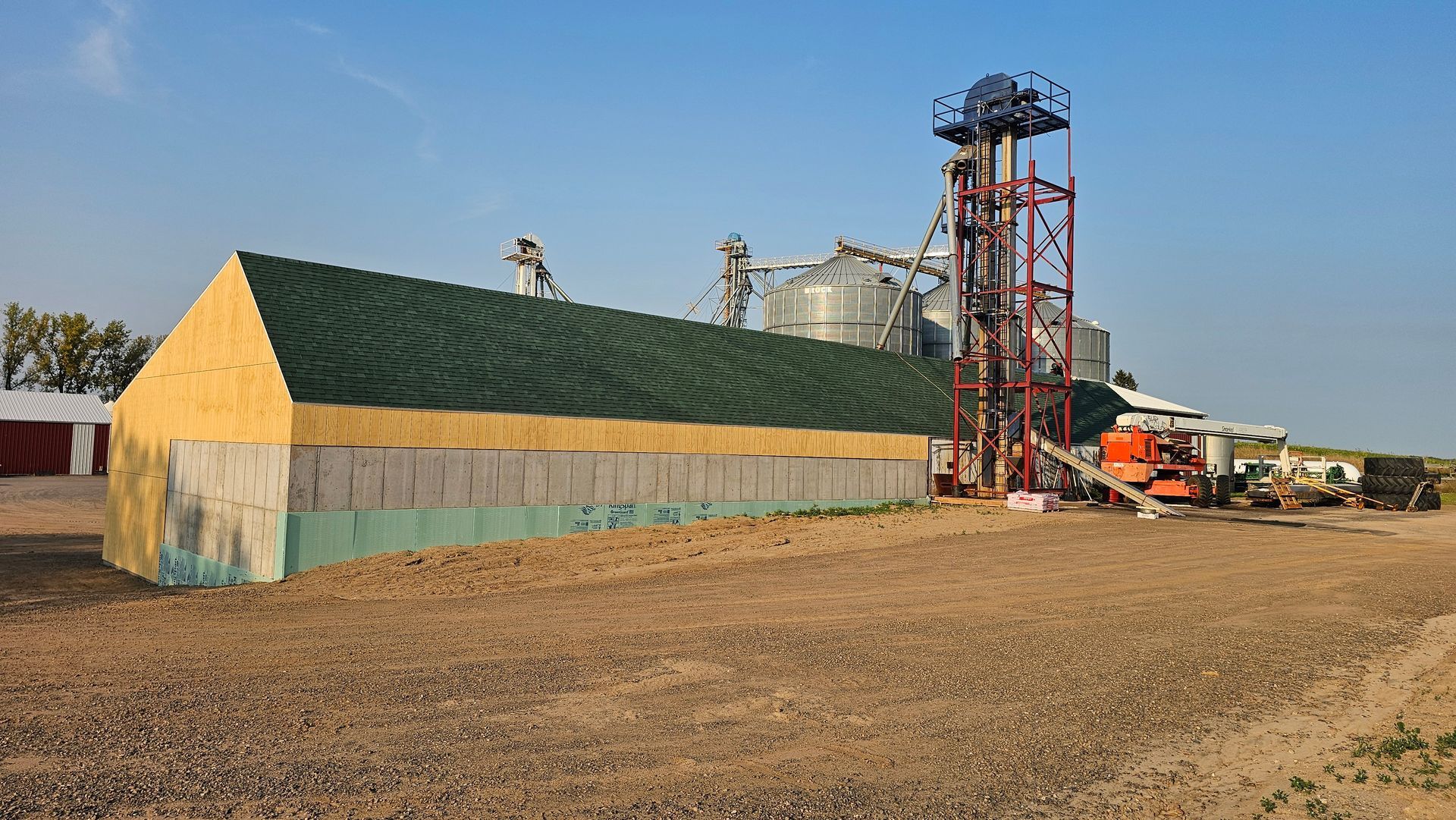 A building with a green roof is sitting in the middle of a dirt field.